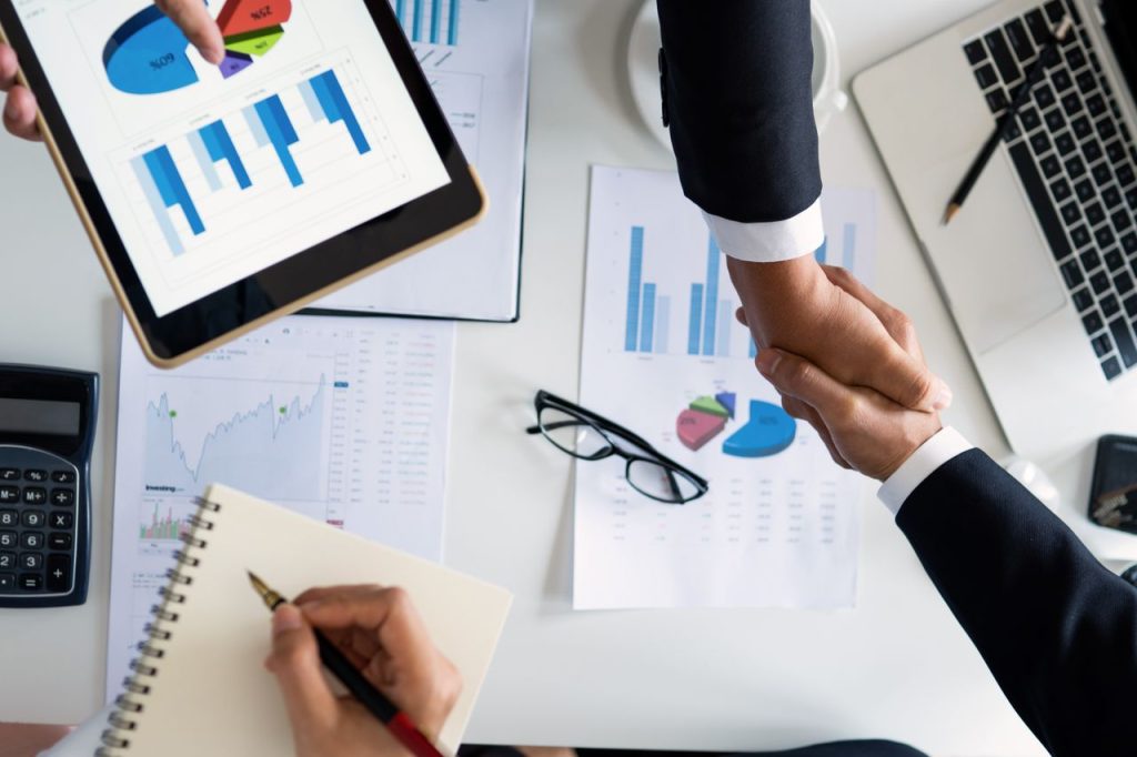 pexels-photo-4175023-1 Business professionals handshake over graphs and charts in a corporate setting, symbolizing successful negotiation and agreement.